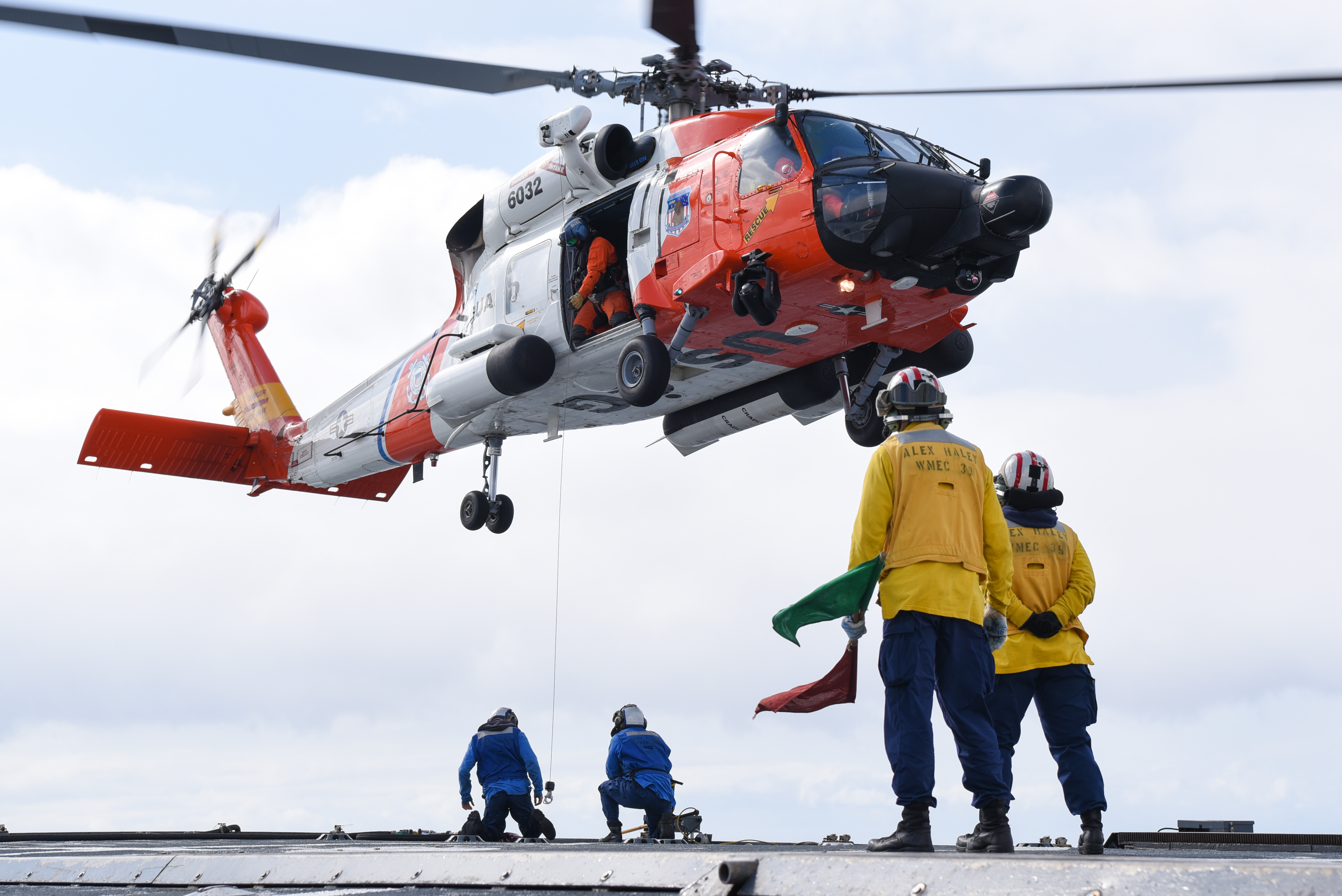 Coast Guard MH-60 Jayhawk helicopter crew lowers hoisting cable to crew members on flight deck of Coast Guard Cutter Alex Haley while underway in Bering Sea, April 8, 2024 (U.S. Coast Guard/John Hightower)